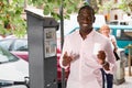 Cheerful African American man showing ticket for car parking purchased in parking meter on city street Royalty Free Stock Photo