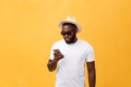 Cheerful African American man in white shirt using mobile phone application. happy dark skinned hipster guy read news