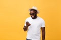 Cheerful African American man in white shirt using mobile phone application. happy dark skinned hipster guy read news