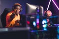 Cheerful African-American in an orange hoodie sitting in a cyber cafe, winning another match with his companions Royalty Free Stock Photo