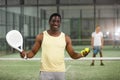 Cheerful african american paddle tennis player on indoor court