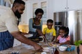 Cheerful african american parents serving pancakes to playful children on messy kitchen island