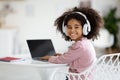 Cheerful african american girl using headphones and laptop, mockup Royalty Free Stock Photo