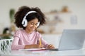 Cheerful african american schooler sitting in front of laptop Royalty Free Stock Photo