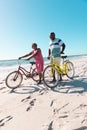 Cheerful african american senior couple with bicycles talking and walking at beach under clear sky Royalty Free Stock Photo