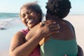 Cheerful african american senior woman embracing young daughter while enjoying vacation at beach Royalty Free Stock Photo