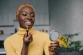 Cheerful african american woman applying lip gloss and looking Royalty Free Stock Photo