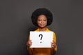 Cheerful african american woman showing card with question mark on black background. Idea concept