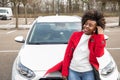 a cheerful african american woman stands next to the White car and laughing Royalty Free Stock Photo