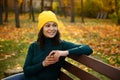 Cheerful African American woman wearing bright colorful warm clothes, yellow hat and green sweater , enjoys coffee break outdoor Royalty Free Stock Photo