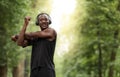 Cheerful african sportsman exercising at park, stretching arms