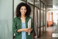 Cheerful african beautiful girl student smiling looking at camera holding books in university. Education concept. Royalty Free Stock Photo