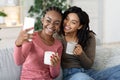 Cheerful african besties taking selfie together at home