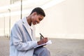 cheerful african business woman writing on a paper notebook with a pen on a bench outdoors Royalty Free Stock Photo