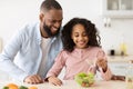 Cheerful african father and daughter cooking salad Royalty Free Stock Photo