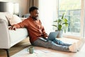 Cheerful African Guy Using Laptop Sitting On Floor At Home Royalty Free Stock Photo