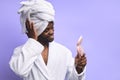 Cheerful african man in bathrobe and towel looking at pink small mirror Royalty Free Stock Photo