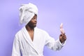 Cheerful african man in bathrobe and towel looking at pink small mirror Royalty Free Stock Photo
