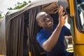 cheerful african man driving a tuk tuk taxi smiling on a very sunny day waving to a passenger Royalty Free Stock Photo