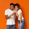 Cheerful african man and woman listening to music on cellphone