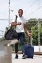 Cheerful african traveler using cell phone at train station