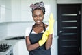 Cheerful african woman wearing rubber gloves standing in the kitchen Royalty Free Stock Photo