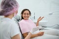 Cheerful African woman sitting in dentists chair at planned regular dental check-up in white dentistry clinic with contemporary