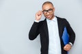 Cheerful african young businessman in glasses with blue folder Royalty Free Stock Photo