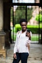 Cheerful beautiful afro american female making selfie on front camera of telephone for publishing in social networks outdoors in c