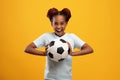 Cheerful afro-american girl holding soccer ball on yellow Royalty Free Stock Photo