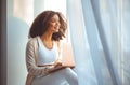 Happy african american young woman freelancer on windowsill with laptop on laps, working from home Royalty Free Stock Photo