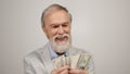 Cheerful aged man holding money indoors. Old guy having fun in modern studio.