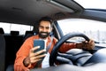 Cheerful arab driver man texting on smartphone while driving car Royalty Free Stock Photo