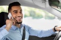 Cheerful arab man talking on cellphone while driving car, closeup Royalty Free Stock Photo