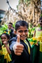 Cheerful Asian boy in a suit shows his thumb up against the background of other children