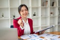 A cheerful Asian businesswoman sits at her desk with financial reports and laptop Royalty Free Stock Photo