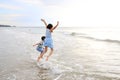Cheerful Asian child girl and little boy having fun jumping on wave at tropical sand beach at sunset. Happy family enjoy in summer Royalty Free Stock Photo