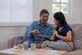 Cheerful Asian couple using network video call tablet sitting together on sofa at home Asian elderly husband sitting Royalty Free Stock Photo