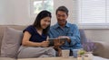 Cheerful Asian couple using network video call tablet sitting together on sofa at home Asian elderly husband sitting Royalty Free Stock Photo