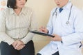 Cheerful Asian doctor talking with young woman patient for monitoring.