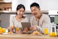Cheerful asian family using digital tablet while having breakfast Royalty Free Stock Photo
