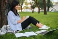 Cheerful asian female student in striped shirt, writing in notebook, while studying in park, outdoor Royalty Free Stock Photo