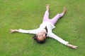 Cheerful Asian girl child lying down on green lawn. Happy kid lies on grass and looking at camera Royalty Free Stock Photo