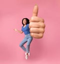 Cheerful Asian Girl Jumping In Air And Showing Thumb Up Royalty Free Stock Photo