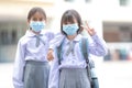 Cheerful Asian kids in student uniforms with medical face masks during pandemic - back to school