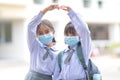 Cheerful Asian kids in student uniforms with medical face masks during pandemic - back to school