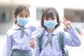 Cheerful Asian kids in student uniforms with medical face masks during pandemic - back to school