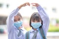 Cheerful Asian kids in student uniforms with medical face masks during pandemic - back to school