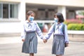 Cheerful Asian kids in student uniforms with medical face masks during pandemic - back to school