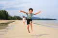 Cheerful Asian little boy child and girl kid having fun jumping and running on tropical sand beach at sunrise. Happy family sister Royalty Free Stock Photo